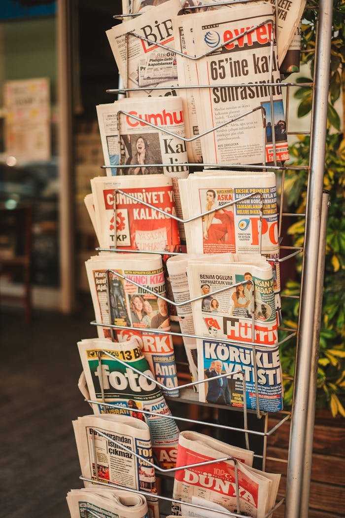 Stack of diverse newspapers in a metal stand, showcasing media variety.