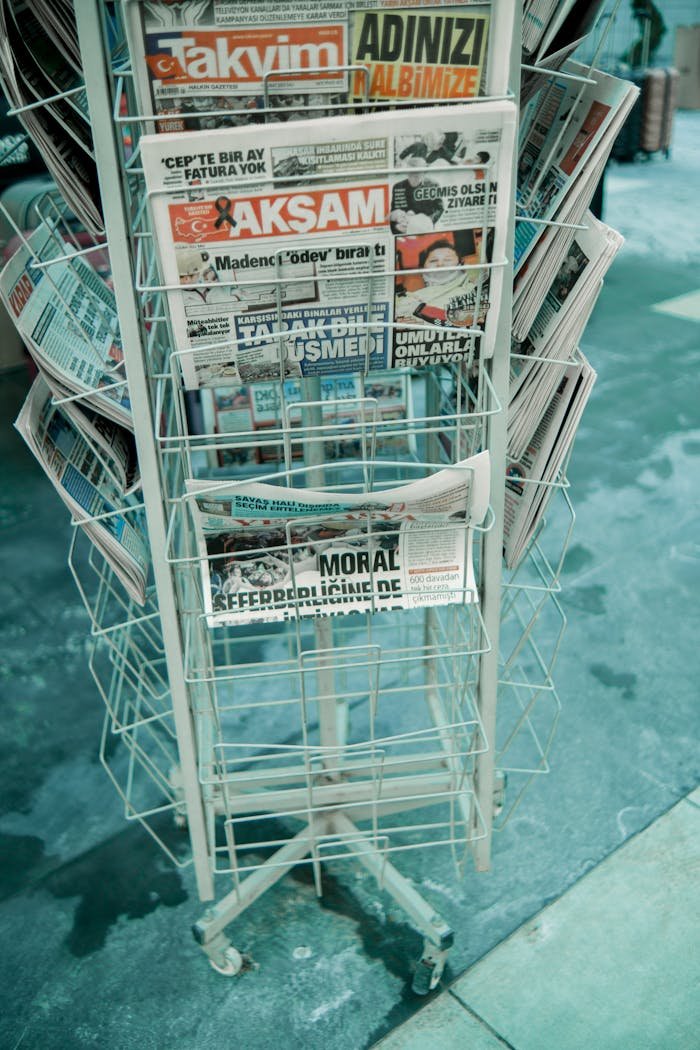 Vertical shot of a street newspaper stand displaying various printed newspapers.